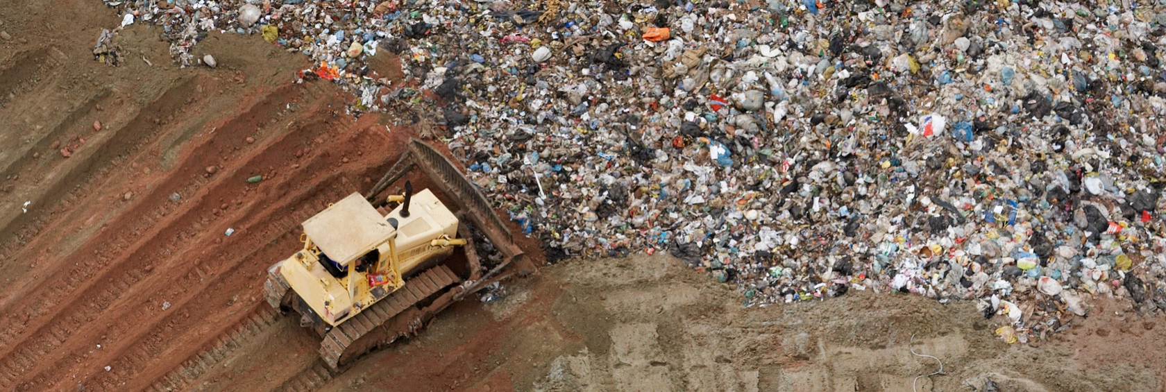 Bulldozer pushing garbage in landfill